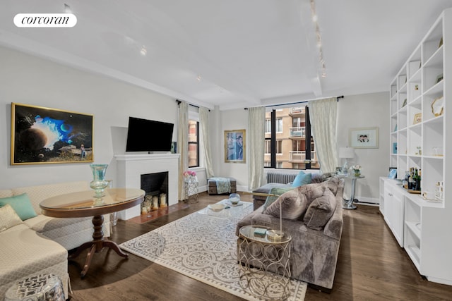 living room featuring dark hardwood / wood-style flooring, track lighting, and beamed ceiling