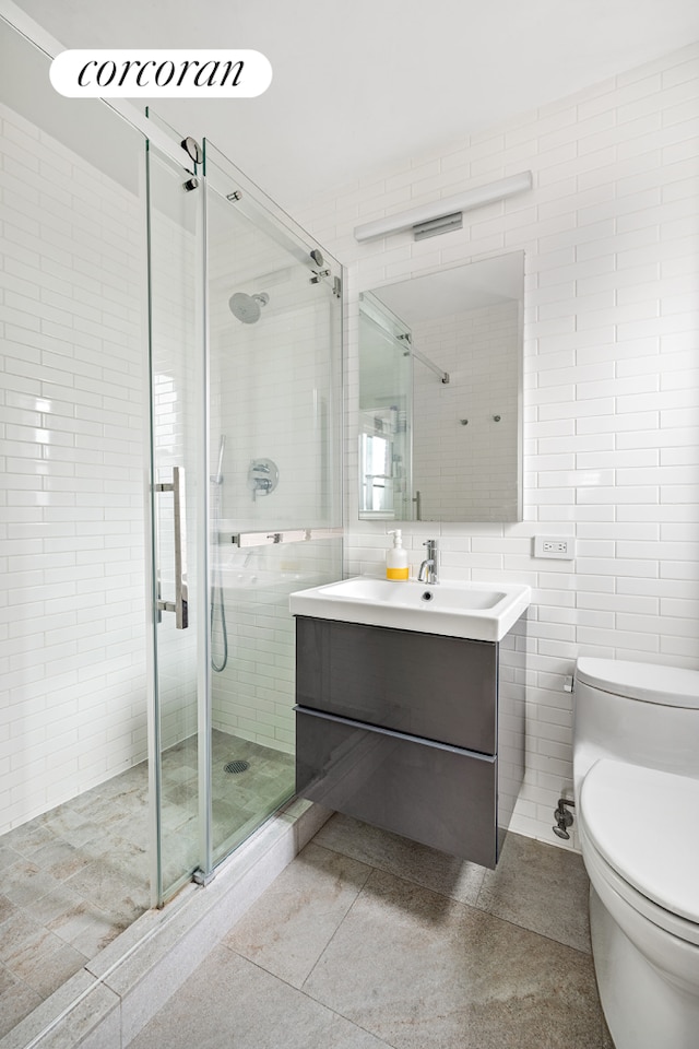 full bath with tile walls, toilet, vanity, and a stall shower