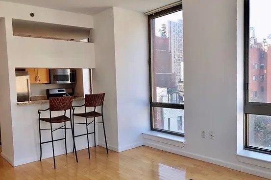 kitchen with stainless steel appliances, expansive windows, a breakfast bar area, and light hardwood / wood-style flooring