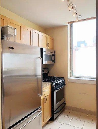 kitchen featuring appliances with stainless steel finishes, rail lighting, light tile patterned floors, baseboards, and light countertops