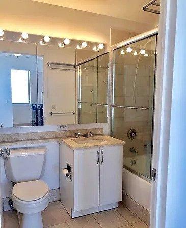 full bathroom featuring tile patterned flooring, toilet, shower / bath combination with glass door, and vanity