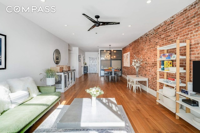 living area with baseboards, brick wall, ceiling fan, wood finished floors, and recessed lighting