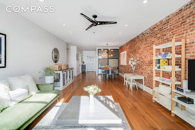 living room featuring brick wall, a ceiling fan, wood finished floors, and recessed lighting