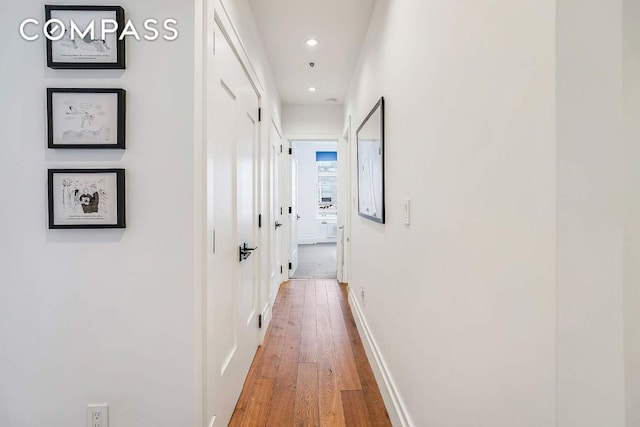 hall featuring baseboards, wood finished floors, and recessed lighting