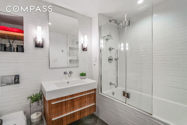 full bath featuring backsplash, shower / bath combination with glass door, tile walls, and vanity