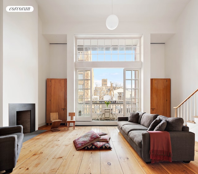 living area with a fireplace with flush hearth, a city view, hardwood / wood-style flooring, stairway, and a high ceiling