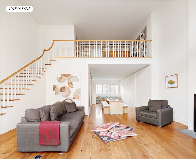 living area with stairs, a high ceiling, visible vents, and hardwood / wood-style flooring