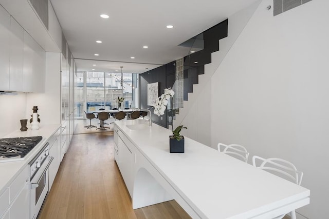 kitchen with a sink, white cabinets, stainless steel oven, light countertops, and recessed lighting