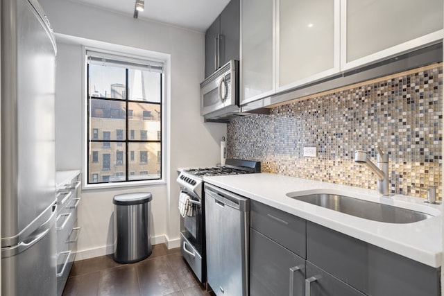 kitchen with gray cabinetry, a sink, light countertops, appliances with stainless steel finishes, and decorative backsplash