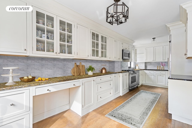 kitchen featuring decorative backsplash, light wood finished floors, appliances with stainless steel finishes, white cabinetry, and a notable chandelier