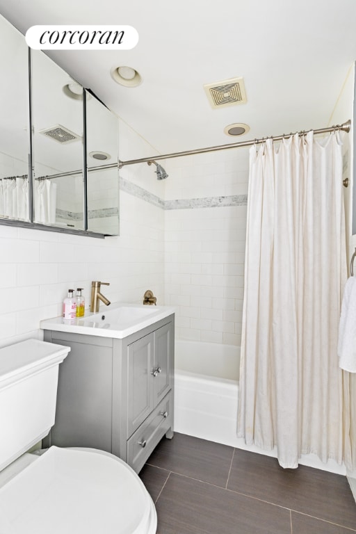 full bathroom with shower / tub combo with curtain, vanity, toilet, and tile walls