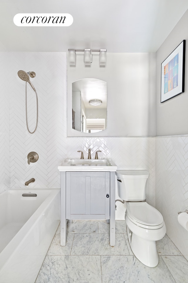 full bathroom with a wainscoted wall, toilet, vanity, shower / washtub combination, and tile walls
