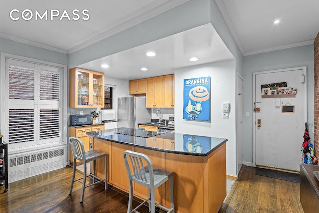 kitchen with crown molding, radiator heating unit, black appliances, a kitchen bar, and dark hardwood / wood-style flooring