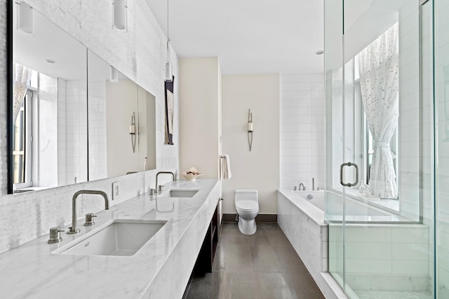 bathroom featuring a stall shower, toilet, a garden tub, baseboards, and double vanity