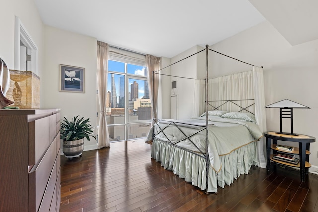 bedroom with wood finished floors, a view of skyline, and baseboards
