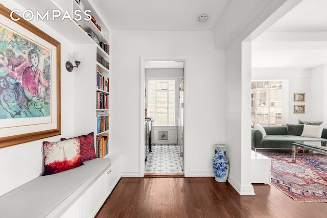 hall with dark wood-style floors, built in features, and baseboards