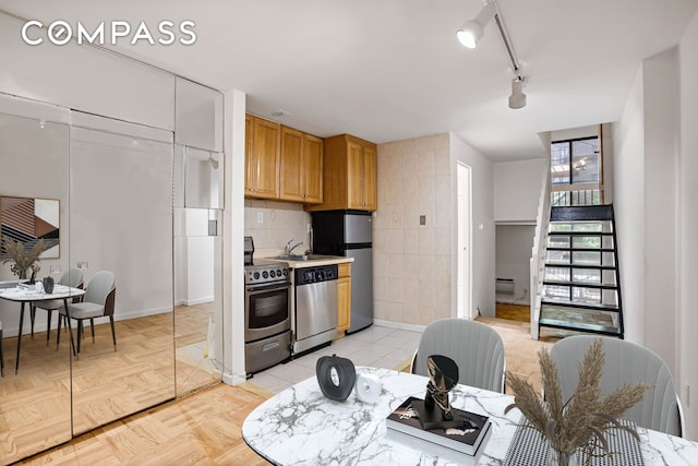 kitchen with decorative backsplash, baseboard heating, stainless steel appliances, light countertops, and a sink