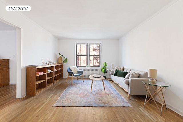 living room with baseboards, visible vents, radiator, crown molding, and light wood-style floors