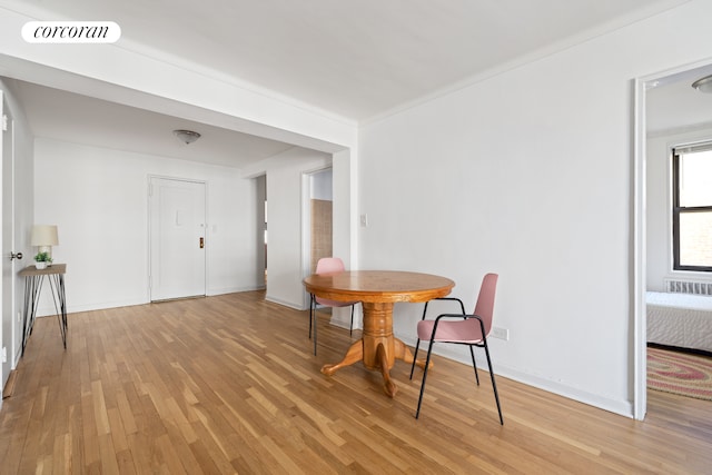 dining space with radiator heating unit, visible vents, light wood-style flooring, and baseboards