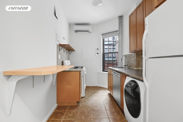 kitchen featuring white appliances, sink, a wall mounted air conditioner, washer / dryer, and dark tile patterned floors