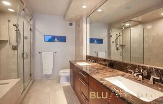 bathroom featuring a stall shower, recessed lighting, toilet, double vanity, and a bath