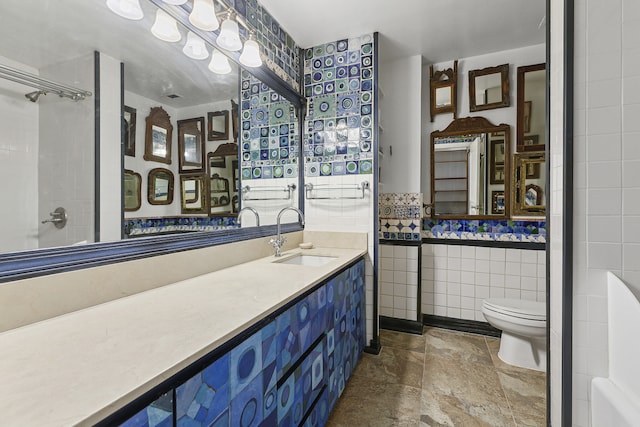full bathroom featuring tile walls, toilet, vanity, stone finish flooring, and a shower