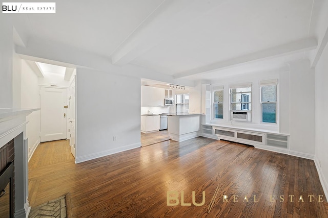 unfurnished living room with baseboards, radiator, a fireplace with flush hearth, beamed ceiling, and wood finished floors