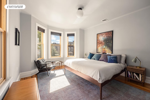 bedroom with wood finished floors, visible vents, and baseboards