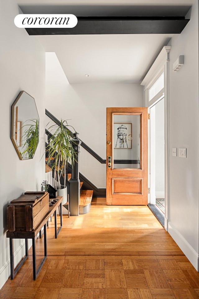 hallway with stairway, baseboards, and parquet flooring