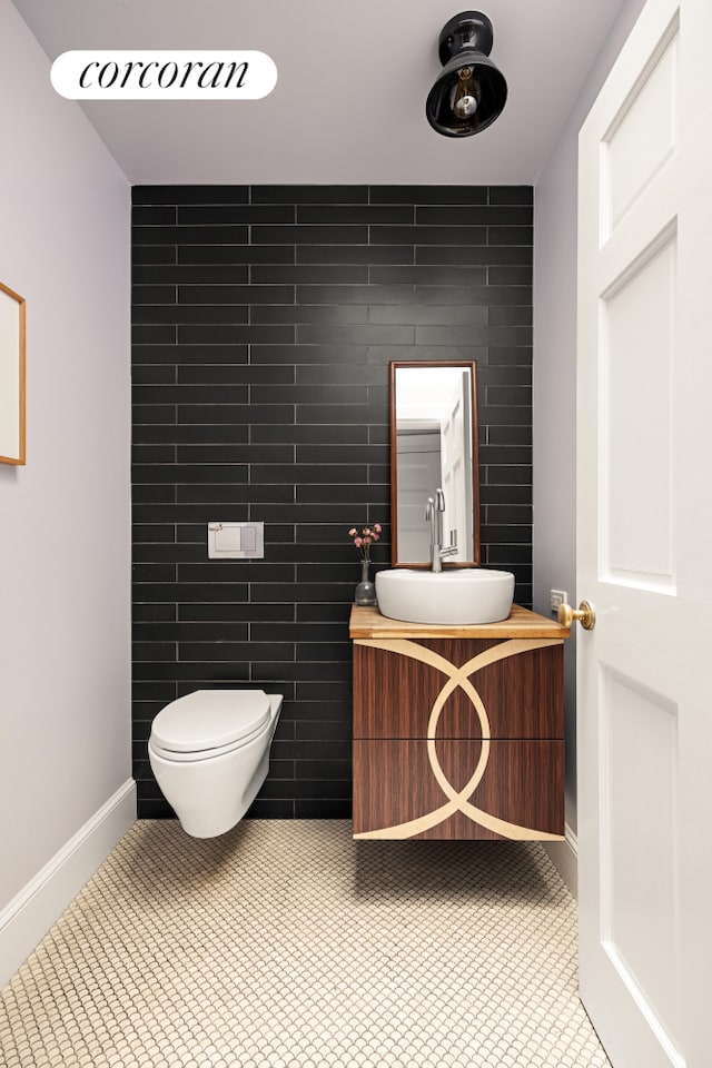 bathroom featuring baseboards, toilet, tile patterned floors, vanity, and tile walls