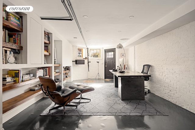 office area featuring concrete flooring and brick wall