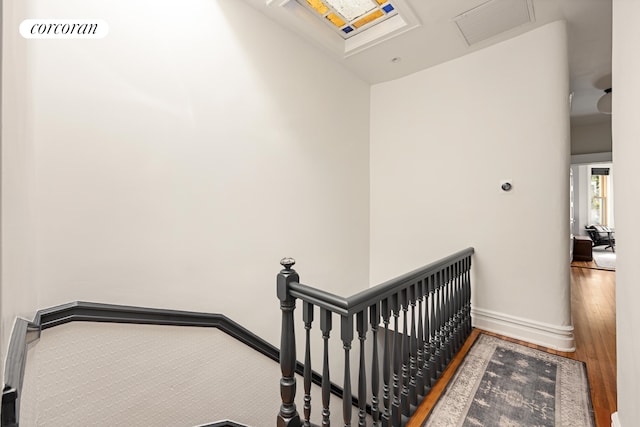 stairway featuring visible vents, baseboards, and wood finished floors