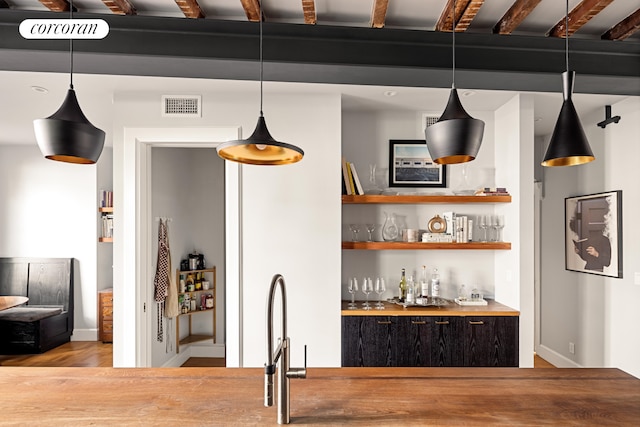 bar with hanging light fixtures, light wood-style floors, visible vents, and a dry bar