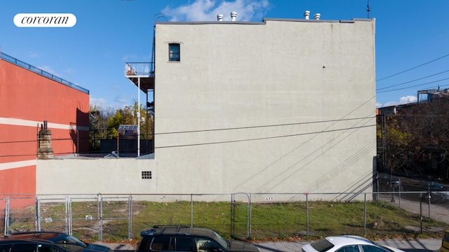 view of side of home featuring fence and stucco siding