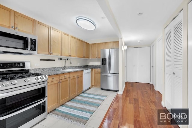 kitchen with a sink, light brown cabinets, stainless steel appliances, and light wood-style flooring
