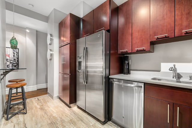 kitchen with sink, appliances with stainless steel finishes, and light hardwood / wood-style flooring