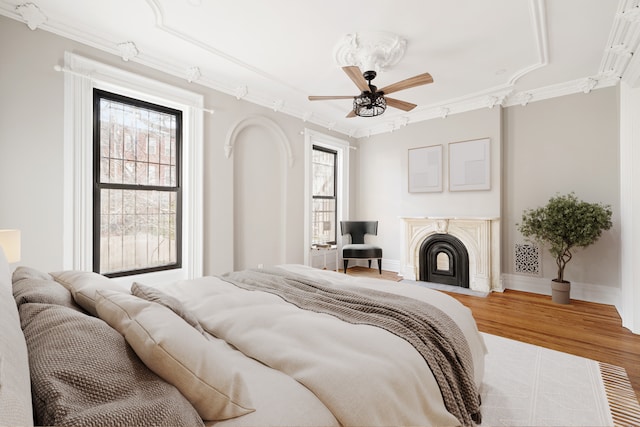 46 Clifton Place, New York City, NY 11238 - bedroom featuring crown molding, wood finished floors, a fireplace with flush hearth, a ceiling fan, and baseboards