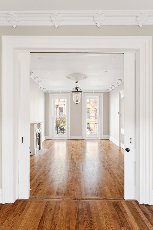 46 Clifton Place, New York City, NY 11238 - unfurnished living room featuring wood finished floors, a chandelier, ornamental molding, baseboards, and washer / clothes dryer