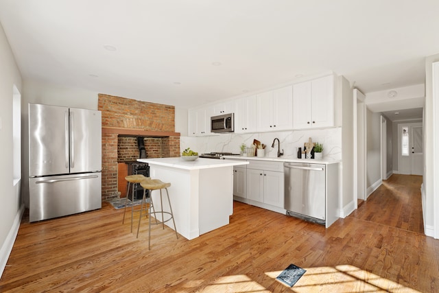 46 Clifton Place, New York City, NY 11238 - kitchen with stainless steel appliances, a kitchen island, light countertops, white cabinetry, and light wood-style flooring