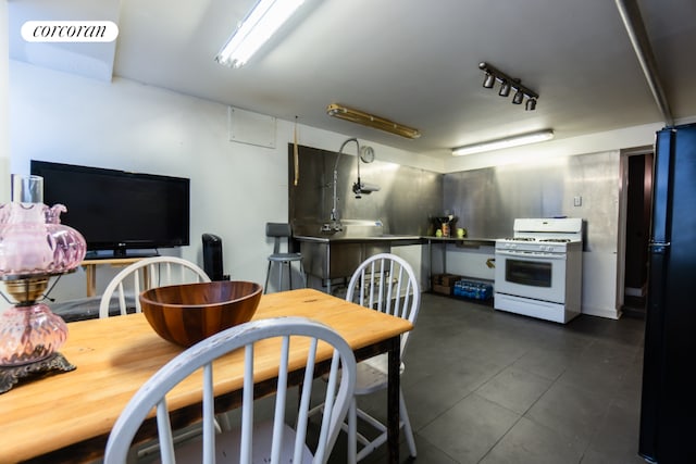 kitchen featuring black fridge, white gas range, and rail lighting