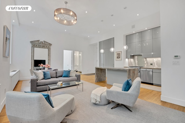 living room with light hardwood / wood-style floors, a chandelier, and a towering ceiling