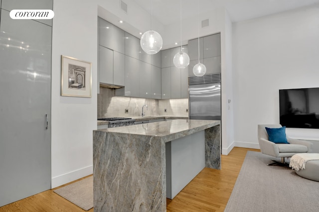 kitchen featuring light stone countertops, light wood-style flooring, modern cabinets, and stainless steel appliances