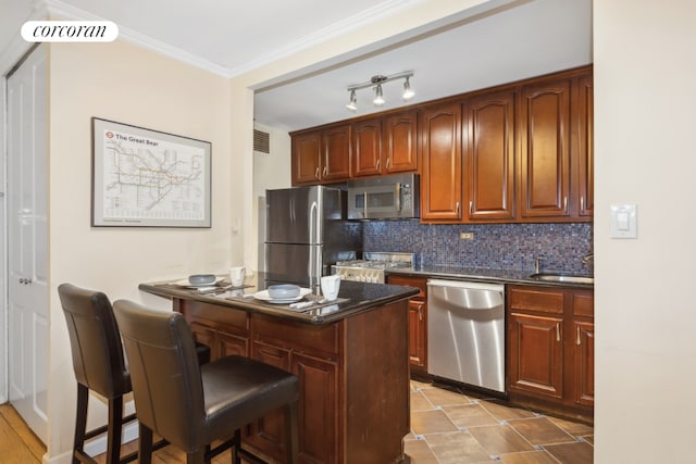 kitchen with sink, a breakfast bar, stainless steel appliances, ornamental molding, and tasteful backsplash