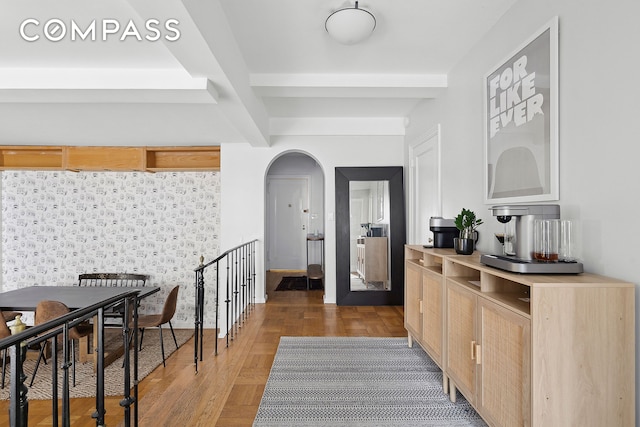 interior space featuring arched walkways, beam ceiling, and parquet floors