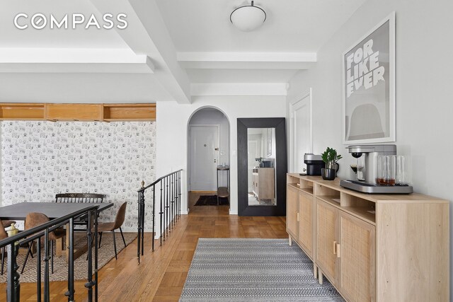 interior space featuring arched walkways, beam ceiling, and parquet floors