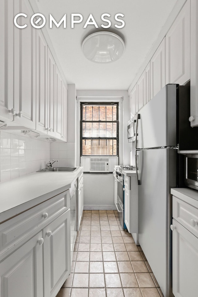 235 E 73rd St Unit 1D, New York City, NY 10021 - kitchen with appliances with stainless steel finishes, a sink, white cabinetry, and light countertops