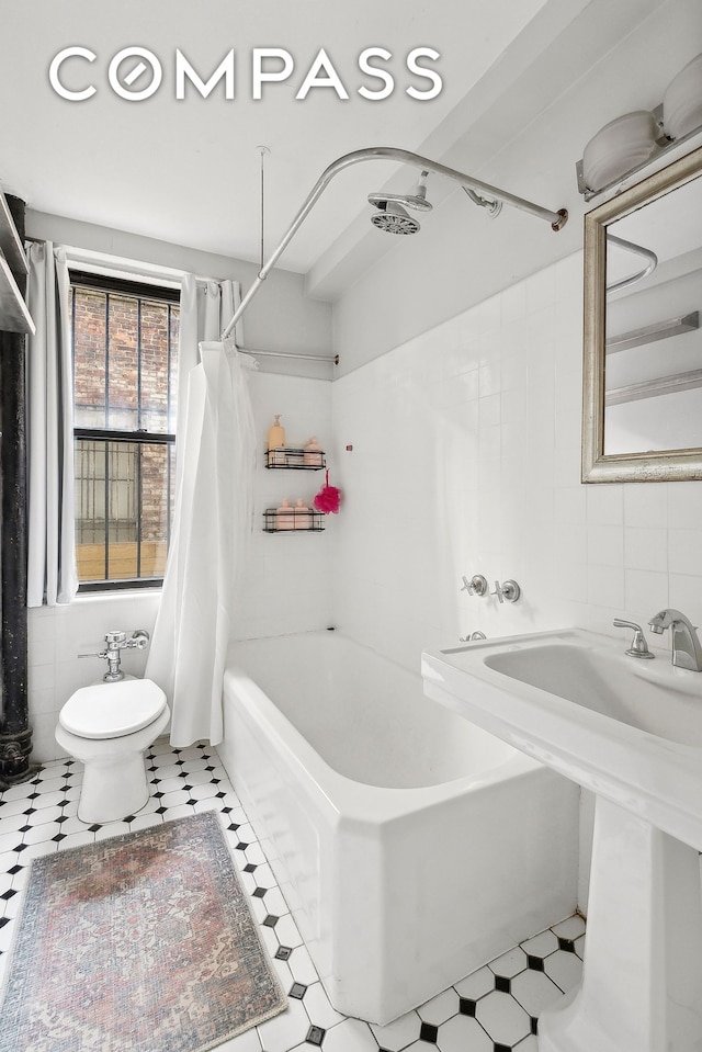 full bath with tile patterned floors, shower / tub combo, tile walls, and toilet