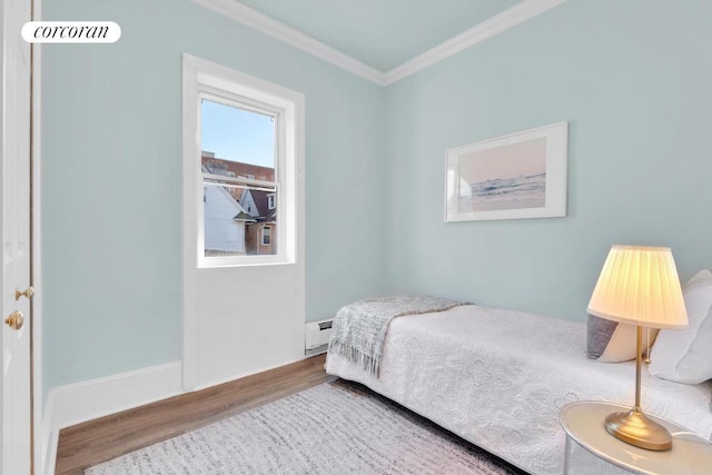 bedroom with baseboard heating, ornamental molding, and wood-type flooring