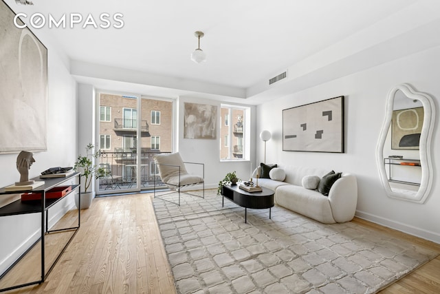 living room featuring baseboards, wood finished floors, and a healthy amount of sunlight