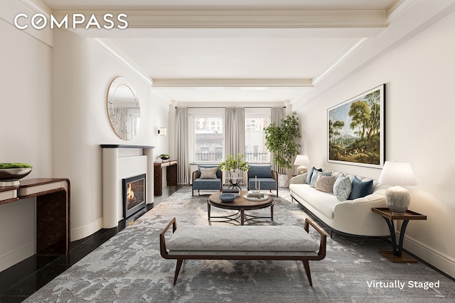 living area with granite finish floor, baseboards, ornamental molding, and a glass covered fireplace